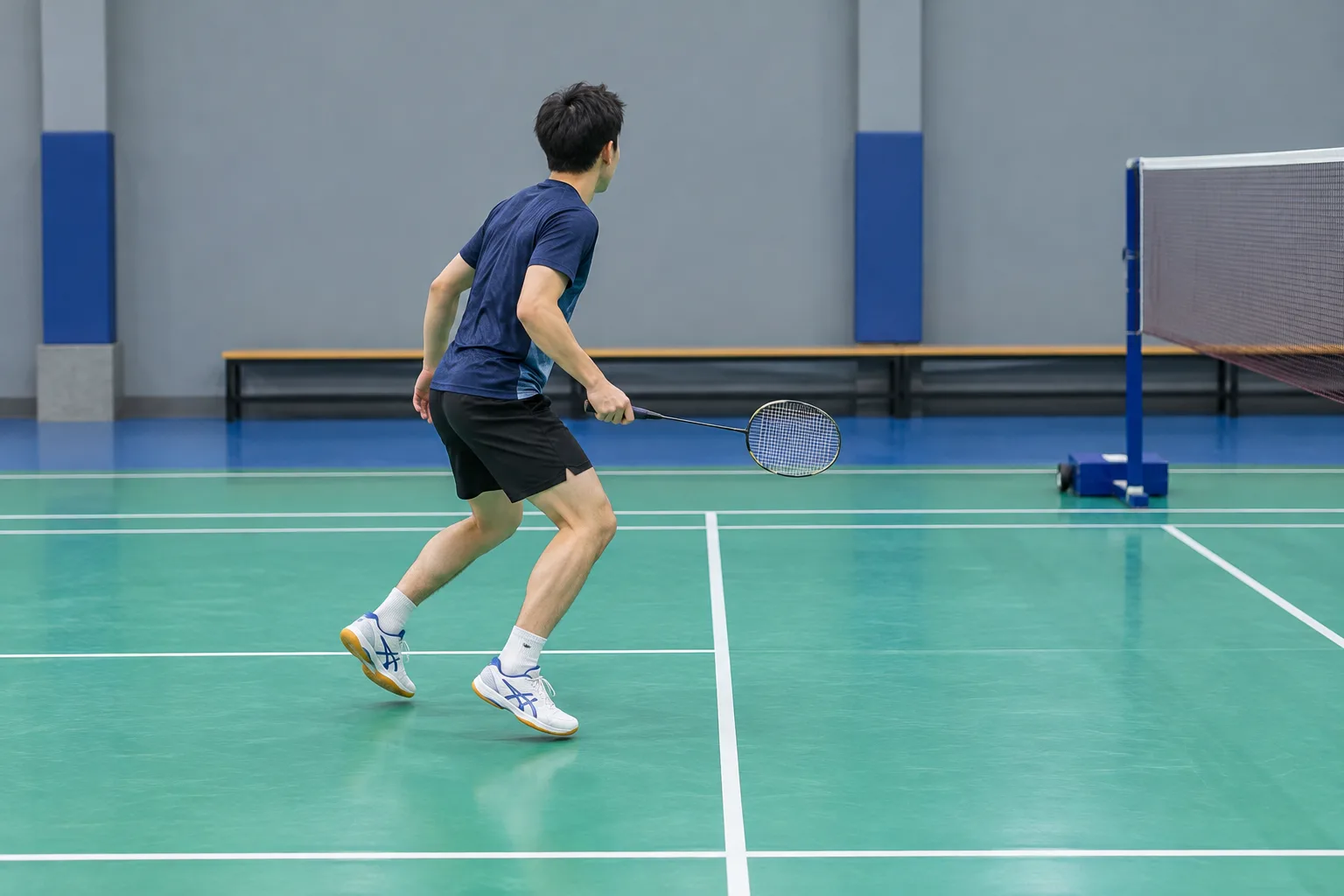 Un joueur de badminton travaille ses appuis et revient vers le centre du terrain.
